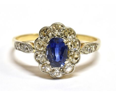 A SAPPHIRE AND DIAMOND OVAL CLUSTER 18CT GOLD RING WITH DIAMOND SET SHOULDERS  the central oval mixed cut blue sapphire measu