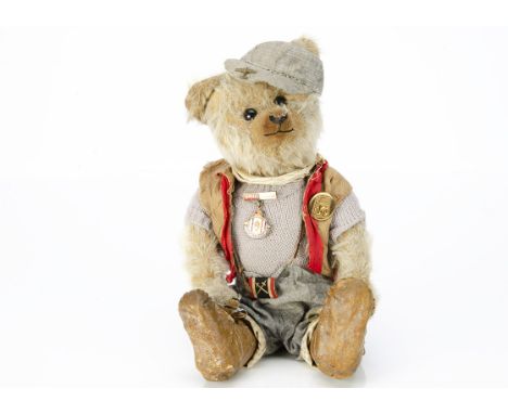 A dressed German teddy bear 1910-1920,  with blonde mohair, black boot button eyes, upturned clipped muzzle, black stitched n