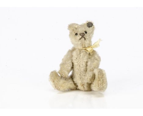 A Steiff miniature white mohair teddy bear 1920s, with black boot button eyes, brown stitched nose and mouth, swivel head, jo