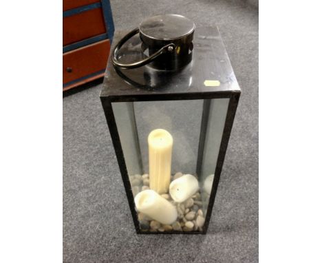 A hurricane lamp containing stones and candles 