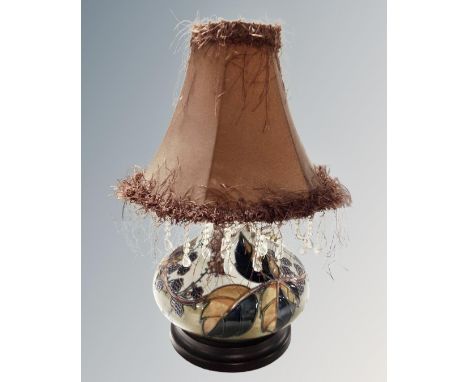 A Moorcroft table lamp decorated with berries on wooden base with tasseled shade 