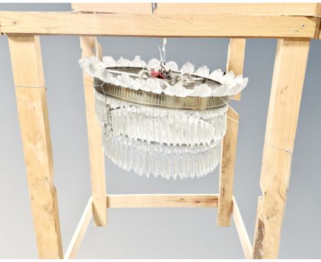 A vintage light fitting with glass drops in hanging pine crate