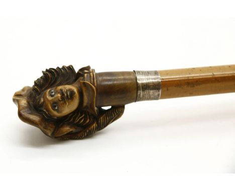 A walking stick, now with with carved head on a cane shaft. 98cm long