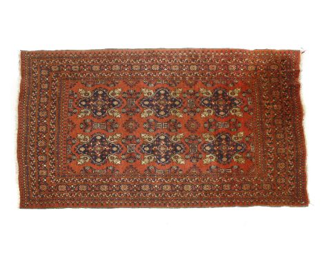 A 20th century Afghan carpet, decorated with six rosettes to the central panel, surrounded by stylised foliage borders on a r