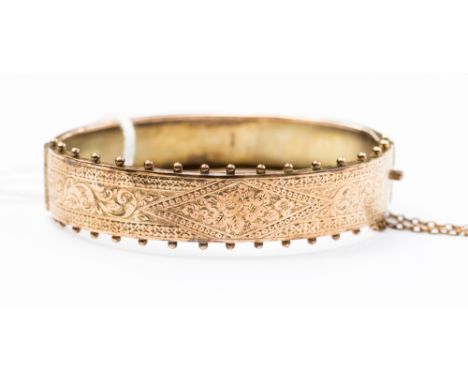 A late Victorian 9ct gold bangle, with an engraved floral design detail with front edge of bangle decorated with ball detail,