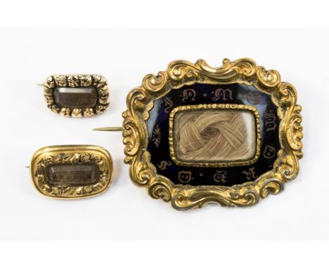 A Victorian mouring brooch with black enamel and gilt metal, with hair window to the front along with Two George III mourning