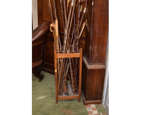 A collection of walking sticks in an oak stick stand to include horn handled sticks and those with carved animals (1) 