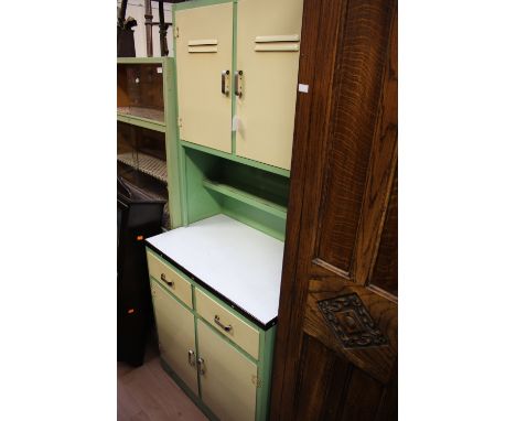A circa 1950's green and cream kitchen unit with various period enamel kitchen vessels