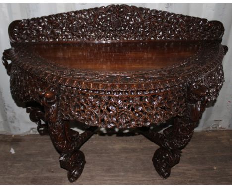  A late 19th Century Burmese carved hardwood demilune console table, elaborately carved and pierced throughout with foliage i