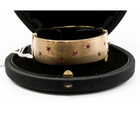 A ruby and 9ct gold hinged bangle star set with seven round rubies, approx width 22mm, with an internal diameter of approx 60