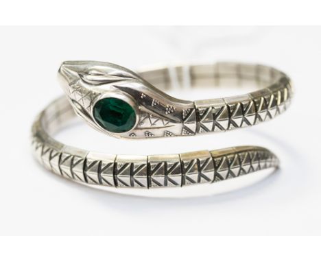 A German Art Deco articulated silver bangle in the form of a serpent, with a paste green stone set to the head, approx diamet