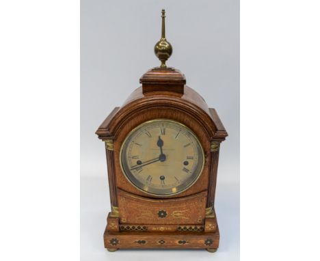 A late 19th /early 20th Century clock, the arched architectural brass inlaid oak case with column supports, surmounted by dom