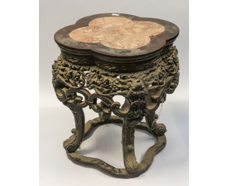 An early 20th Century Chinese carved quatrefoil shaped jardiniere stand, marble top, the apron reticulated with bunches of gr