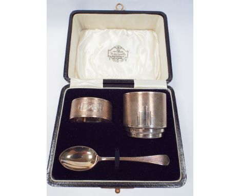 Boxed silver christening set comprising egg cup, spoon and napkin ring Birmingham 1933, engine turned art deco style decorati