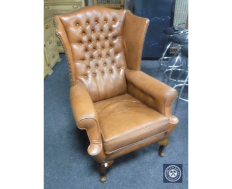 A brown button leather wing back armchair 
