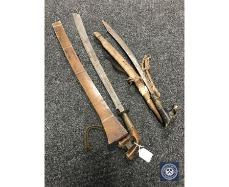 A late 19th century Malayan Parang sword, with 64cm single-edged blade, carved wooden brass mounted hilt, in wooden scabbard,