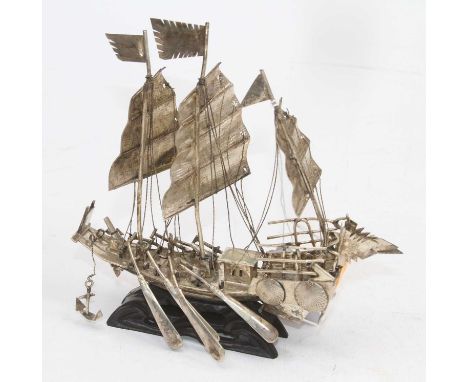 An Eastern white metal model of a junk, mounted upon a carved ebonised wood plinth, h.17cm 