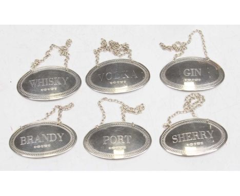 A matched set of six Elizabeth II silver decanter labels for brandy, whisky, gin, port, vodka and sherry, each of oval shape,