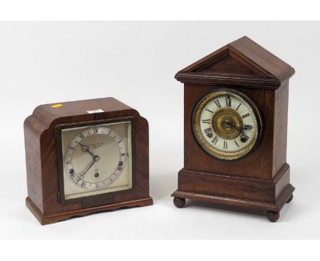 A late 19th century American walnut cased mantel clock, of architectural form, the enamelled chapter ring showing Roman numer
