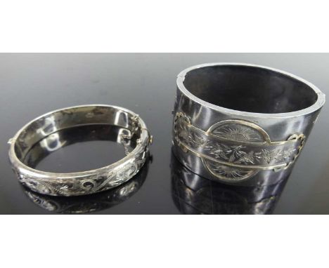 A silver and engraved hinged bangle; together with a silver hinged cuff bangle (2)Both heavily tarnished. Light surface scrat