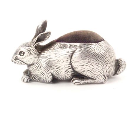 A silver figural pin cushion in the form of a rabbit at rest, Birmingham 1908 by Adie and Lovekin Ltd., 5.8cms wide. From a d