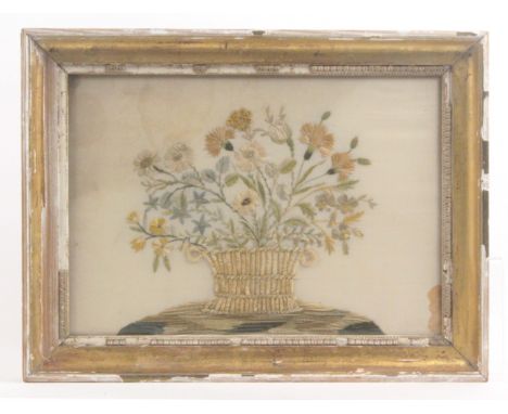 A late 18th Century embroidered silk panel of a basket of flowers, on a grassy mound, staining to background, 23 x 33cms, in 