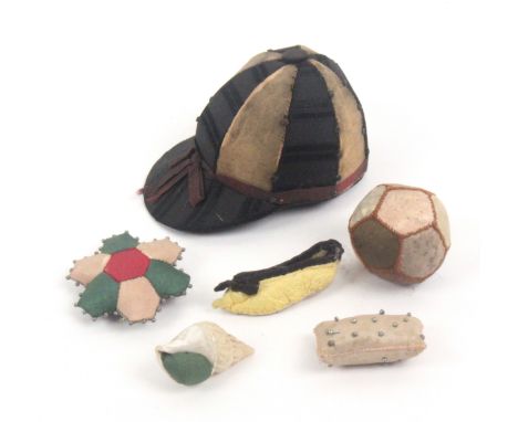 Five pin cushions and a miniature slipper, comprising a jockey cap patchwork example in pink stuck silk segments, 6cms, two d