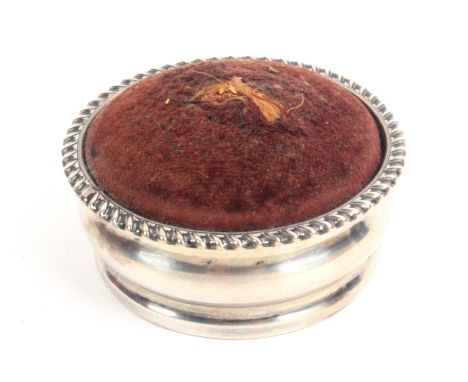 A circular silver pin cushion, domed velvet infill, inset leather base, Birmingham 1901 by Stokes and Ireland Ltd., 6.5cms di