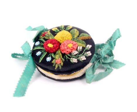 An elaborate needle book in black silk and of circular form, the cover embroidered with leaves and flowers with bead work orn