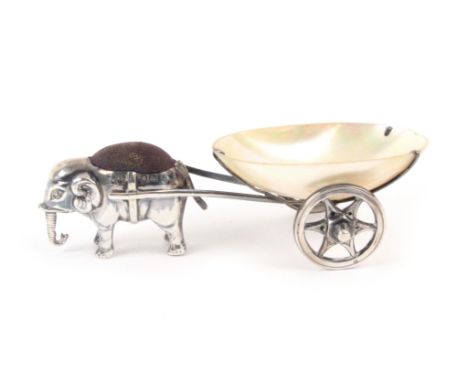 A silver mounted pin cushion and cart, the mother of pearl oval bowl on twin wheel silver cart pulled by an elephant with pin