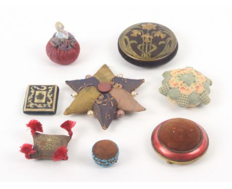 Eight pin cushions and emeries, comprising an embroidered cushion form emery with corner tassels, 6cms, a brown silk pin cush