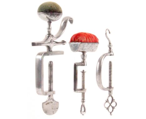 Three polished steel sewing clamps, comprising a 'C' frame example with hook, pierced thread terminal, 11cms, another with re