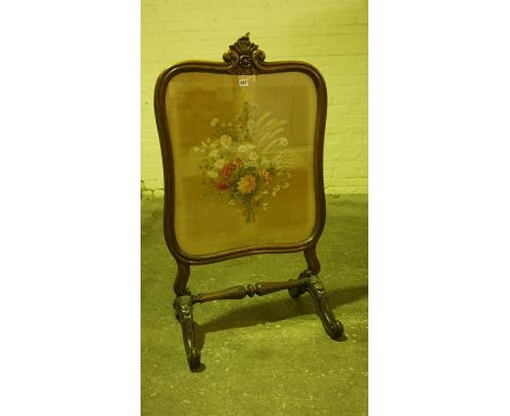 Victorian Rosewood Firescreen, Having a needlepoint floral panel on silk to the front, beneath glass, raised on scroll suppor