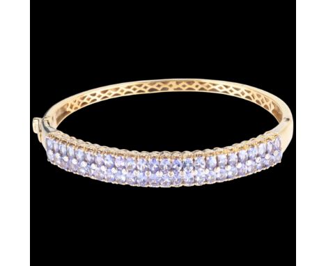 A silver-gilt tanzanite and diamond hinged bangle, setting height 10.1mm, internal circumference 19cm, 22.9g . Condition Repo