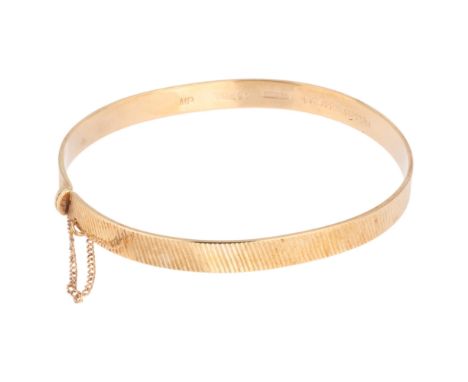 A 9ct gold hinged bangle, maker MP, London 1964, allover fluted decoration, band width 5.8mm, internal circumference 17cm, 10