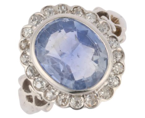 A 14ct white gold sapphire and diamond cluster ring, rub-over set with 4.6ct oval mixed-cut sapphire surrounded by single-cut
