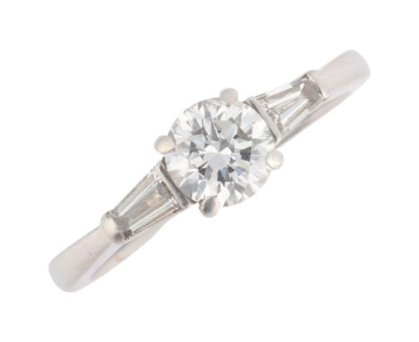A platinum 0.6ct single stone diamond ring, claw set with 0.6ct modern round brilliant-cut diamond, flanked by tapered baguet