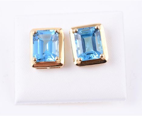 
	
		A pair of blue topaz earrings, the step cut blue topaz in polished settings, stamped 750, 1.2cm long, 4.5g gross

	

