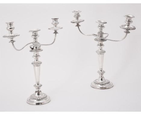 
	
		A pair of electro-plated three light candelabra, with twin scroll branches, gadrooned borders, tapering stems and circul