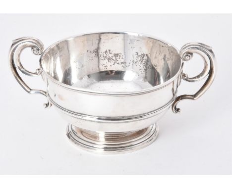 
	
		An Edwardian silver twin handled bowl by William Comyns, London 1902, with twin capped flying scroll handles, a girdle a