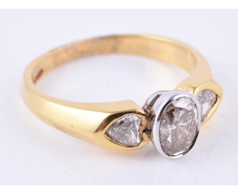 
	
		A diamond three stone ring, the central oval cut diamond rub over set between heart shaped diamond shoulders, approximat