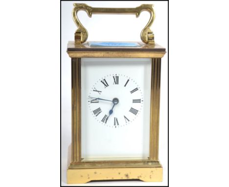 An early 20th century brass carriage clock with open escapement window and handle atop, ceramic face with roman numeral chapt