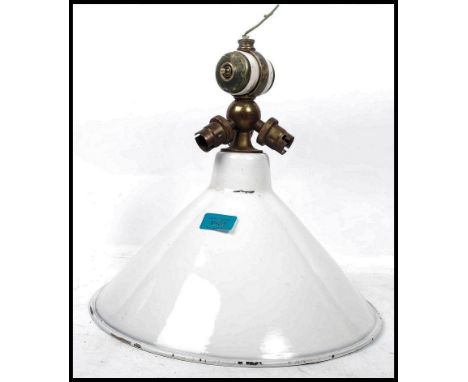 A vintage 20th century retro industrial enamel pendant light fitting having a set of brass switches and bulb holder.