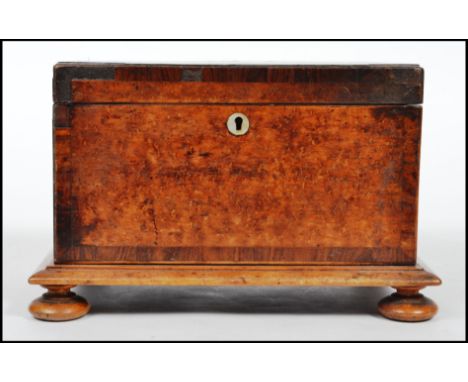 A Victorian 19th century burr walnut tea caddy of square form with hinged lid, sectional interior and raised on bun feet