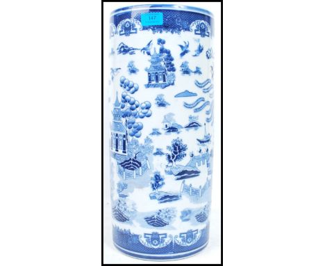 An Oriental ceramic stick stand of tall form having a blue and white decoration depicting scenes of temples and repeating pat
