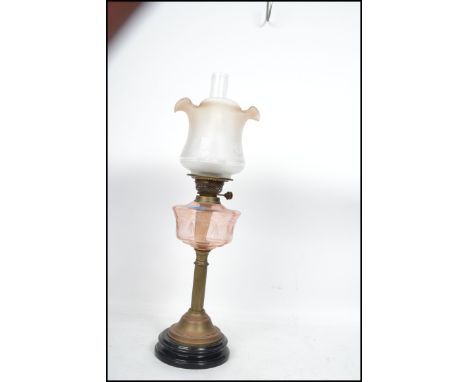An early 20th Century oil lamp having a flute and tulip style shade raised above a faceted reservoir on top of a cast metal t