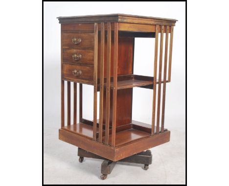 An early 20th century Edwardian mahogany revolving book case having an unusual three drawers to one side being raised on a qu