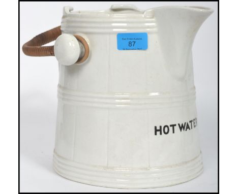 A large early 20th century ceramic water jug fitted with a cane wicker handle and inscription to the front reading Hot Water.
