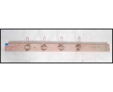 A set of four vintage mounted early 20th century coat hooks each having an individual cast number beneath, mounted on a paint