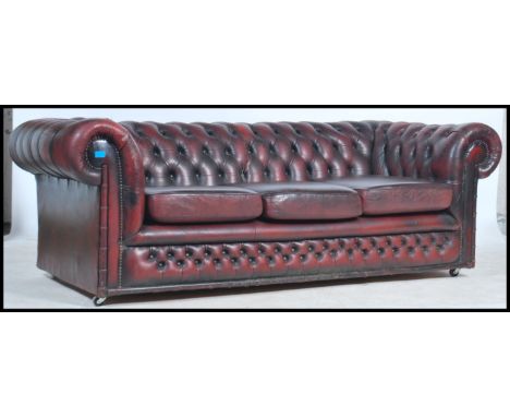 An antique style oxblood red leather Chesterfield sofa settee having buttoned back leather scrolled arms and back rests with 